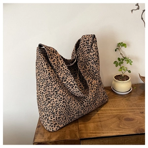 Detail of a leopard print canvas tote bag on a wooden table with green plant decor