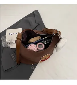 Detail of a large brown tote bag showing spacious interior with teddy bear patch