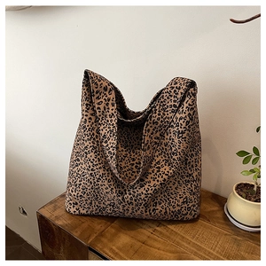 Detail of leopard print canvas tote bag with wide strap on a wooden surface
