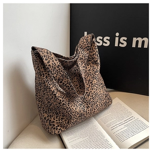 Detail view of large leopard print canvas tote bag with wide strap on white cushion