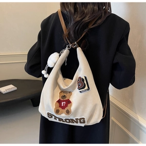 Detail of canvas tote bag featuring teddy bear embroidery and brown leather strap