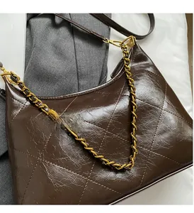 Détail d'un sac matelassé marron avec chaîne dorée et cuir synthétique brillant plissé