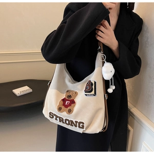 Detail of cream tote bag featuring bear embroidery and soft cloud plush keychain