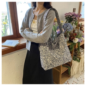Detailed shot of large leopard print canvas shoulder bag worn by model in casual style