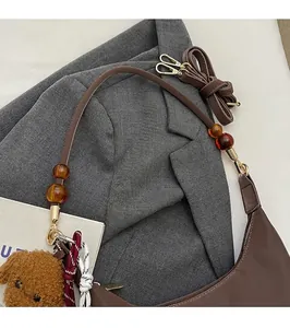 Detalle de bolso bandolera marrón café con cuentas de ámbar y colgante de oso de peluche