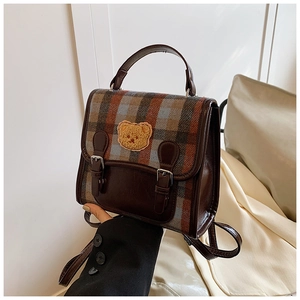 Detail of plaid backpack with teddy bear embroidery and brown leather contrast trim