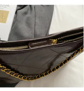 Détail d'un sac en cuir matelassé marron foncé avec fermeture éclair et chaîne