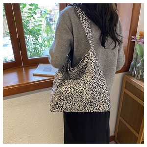 Leopard print canvas tote bag over the shoulder shown on model in cozy home setting