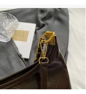 Détail du sac matelassé marron foncé avec accessoires en métal doré et chaîne