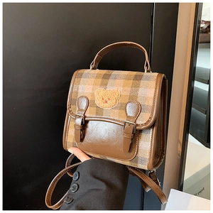 Close-up of retro plaid handbag featuring a cute bear patch and faux leather finish