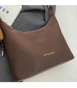 Detalle de bolso tote marrón oscuro con tela suave de calidad y letras doradas de marca