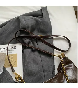 Détail du sac matelassé marron foncé avec chaîne dorée et bandoulière réglable lisse
