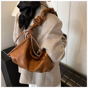 Détail d'un sac à bandoulière marron plissé montrant la texture unique de la lanière