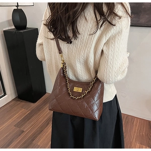 Dettaglio borsa hobo trapuntata marrone con catena dorata indossata da modella