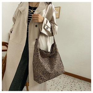 Close-up of leopard print canvas tote bag with a wide shoulder strap on a female model