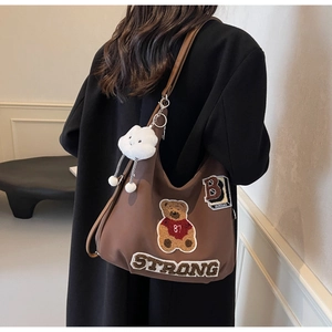Detail of brown tote bag with bear embroidery and white plush cloud pendant accessory