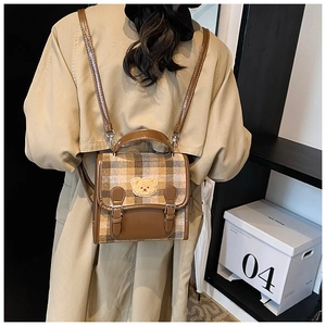 Detail of plaid patterned backpack with cute bear patch and adjustable brown straps