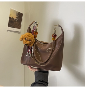Detalle del bolso media luna de nylon café con cuentas de ámbar y dije de perro