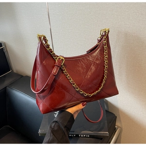 Détail du sac matelassé bordeaux avec finition cuir huilé brillant et chaîne dorée