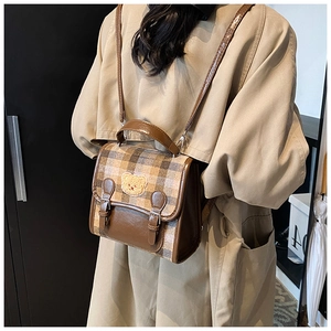 Detail of brown plaid backpack with cute bear embroidery and retro buckle straps