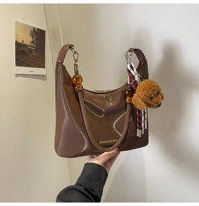 Bolso de hombro marrón brillante con asa de cuentas de ámbar y colgante de osito
