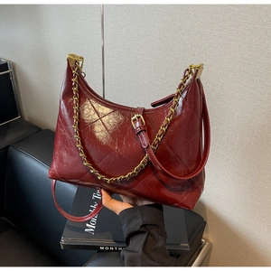 Détail du sac demi-lune bordeaux matelassé avec chaîne dorée et texture losange brillante