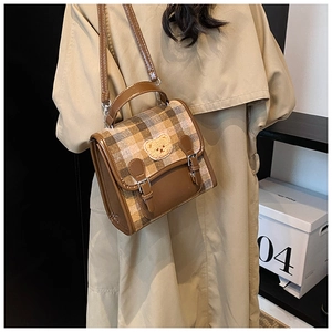 Detail of vintage brown plaid crossbody bag with cute bear patch and metal buckles