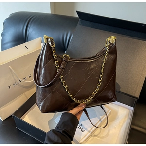 Gros plan du sac bandoulière matelassé marron foncé avec chaîne dorée et fini brillant