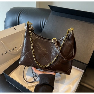 Détail du motif matelassé sur cuir brillant marron foncé avec chaîne dorée élégante