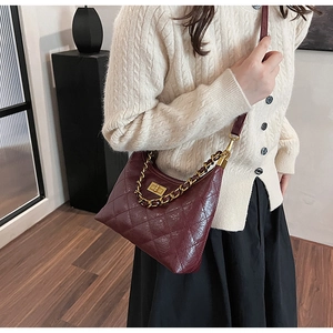 Dettaglio di una borsa in pelle trapuntata bordeaux con chiusura e catena dorata
