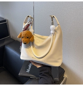 Detalle de bolso de cuero blanco crema con asa de cuentas y colgante de osito