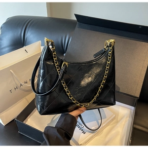 Détail du sac en cuir verni matelassé noir avec chaîne dorée et texture brillante