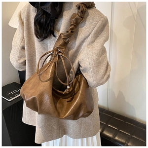 Détail du sac hobo marron foncé avec bandoulière plissée et finitions à cordon de serrage