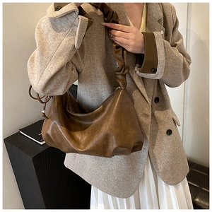 Détail du sac croissant en cuir marron foncé avec bandoulière plissée décorative