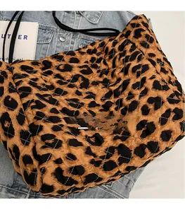 Detail of leopard print quilted tote bag with black straps on denim background