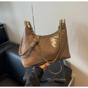 Détail d'un sac hobo en cuir matelassé marron avec chaîne dorée et fini texturé