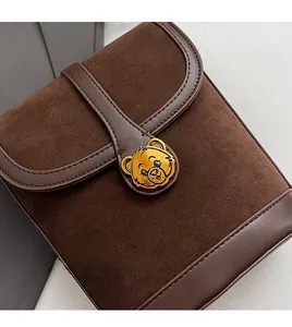 Close-up of dark brown suede bucket bag with gold bear clasp on marble background