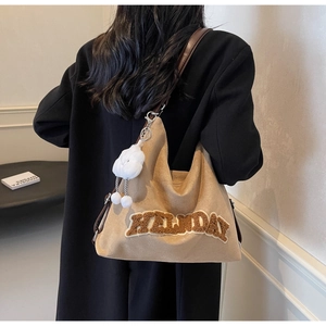Détail du sac cabas en daim camel avec lettrage HOLIDAY en peluche et breloque nuage
