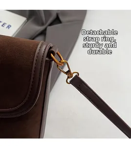 Detail of detachable strap with bronze lobster clasp on brown suede bucket bag