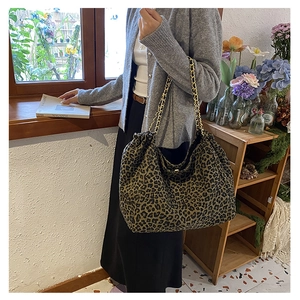 Detail of leopard print tote bag with golden chain strap on a rustic windowsill
