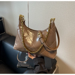 Détail du sac bandoulière marron glacé avec surpiqûres blanches et chaîne dorée