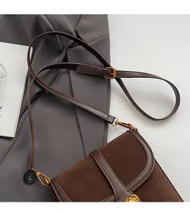Detail of adjustable leather shoulder strap and gold buckle on a brown bucket bag