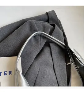 Close-up of metallic silver bucket bag handle paired with a dark grey suit jacket