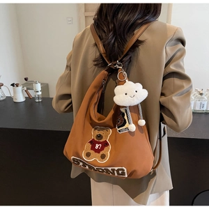 Detail of tan canvas tote bag with teddy bear patch embroidery and white cloud charm