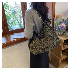 Detail of a large leopard print tote bag featuring a premium gold chain shoulder strap