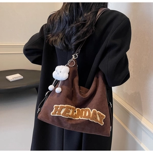 Sac bandoulière marron en daim sur le dos d'un modèle avec pendentif en peluche