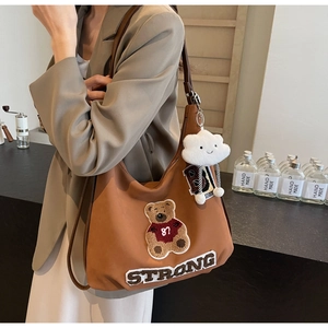 Detailed view of tote bag featuring embroidered bear patch and plush cloud charm accessory