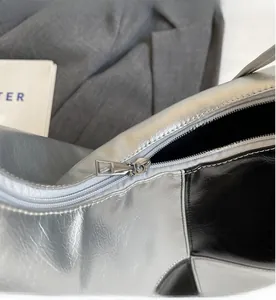 Detail of a smooth metal zipper on a trendy silver and black contrast crossbody bag