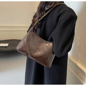 Détail du sac bandoulière marron matelassé avec une bandoulière en chaîne dorée