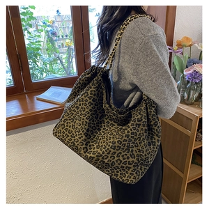 Detail of leopard print tote bag featuring a drawstring closure and gold chain strap